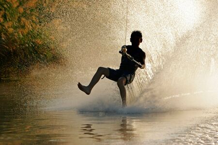 Silhouette of a barefoot skier with backlit water sprayの写真素材
