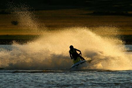 Backlit jet ski with water spray, late afternoonの写真素材