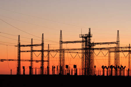 Silhouetted power pylons against a red sky at sunsetの写真素材