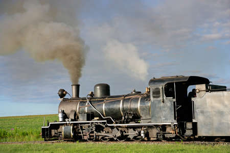 Vintage steam locomotive with billowing smoke and steam
