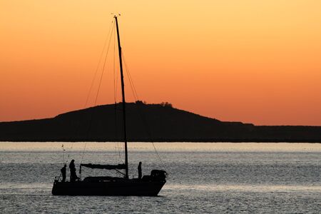 Silhouette of a yacht against a red sunset with reflecting water
の写真素材