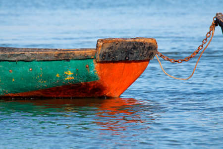 Anchored wooden fishing boat with reflection in water の写真素材