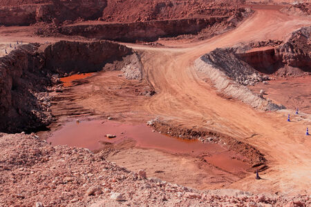 Large, open-pit iron ore mine showing the various layers of soil and iron rich ore