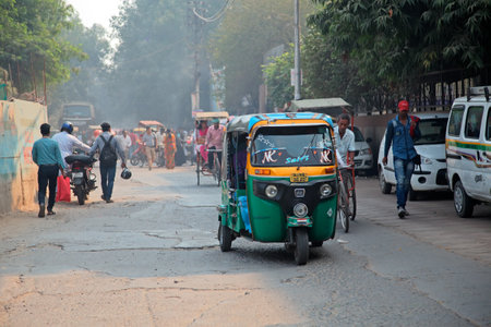 Delhi, India - November 20, 2015: Colorful Tuk-Tuk vehicle and pedestrians in a crowded traffic of...