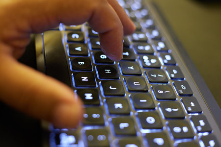 Close-up of a man's hand typing on a laptop keyboard
