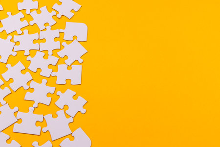 White puzzle pieces in various positions on a yellow background, symbolizing complexity and orderの写真素材