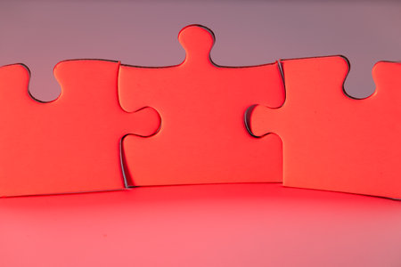 White puzzle pieces standing upright on a white background, illuminated with red light, creating a striking and conceptual visualの写真素材