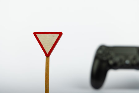 A wooden toy sign with Yield is prominently displayed in focus, while a blurred game controller sits...