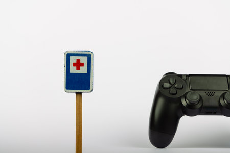 The image shows a wooden toy hospital sign and a video game controller set against a white...