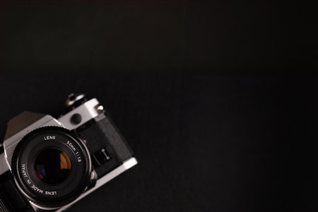 A vintage film camera featured in the left corner with a large black backdrop, showing the elegance of old photography equipment.の写真素材