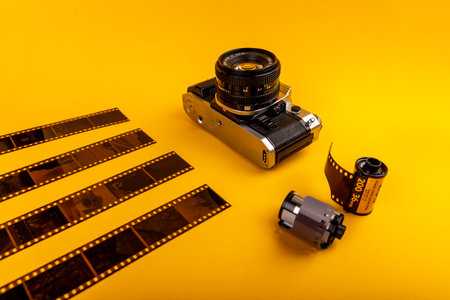 Close-up of an old camera with used 35mm film rolls on a yellow background, capturing the essence of analog photography.の写真素材