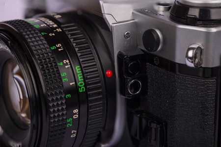 Detailed view of an antique camera with focus on the lens lock mechanism, against a white backdrop. Highlights classic photographic technology.の写真素材