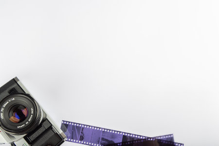 Antique camera with 35mm film rolls and developed film viewed from above on a clean white backdrop. Camera aligned to the left for an artistic touch.の写真素材