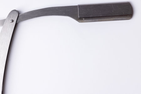 A detailed view of an open barber's straight razor against a clean white background. The blade is prominently displayed on the left side of the image, showing its fine craftsmanship in a top-down perspectiveの写真素材