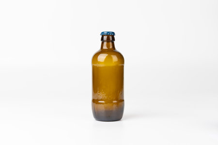 A clear, centered shot of a brown glass beer bottle against a pure white backdrop, emphasizing the product's sleek design in a minimalistic settingの写真素材