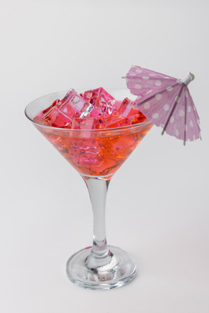 A vertical image shows a detailed view of a red refreshing drink filled with ice and garnished with a lemon slice. The drink is centered on a white backgroundの写真素材