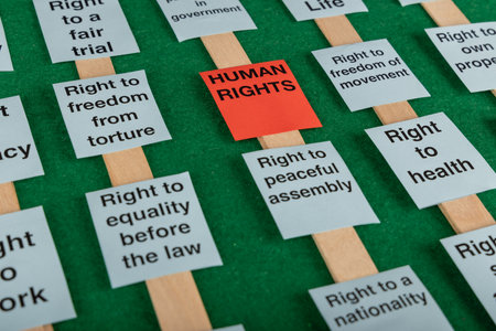 A horizontal image showing various human rights signs on a green background, including a striking red sign emphasizing human rightsの写真素材