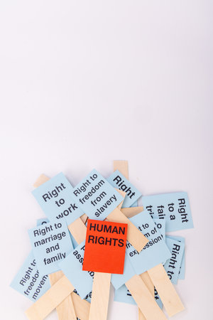 Bright blue signs with scattered human rights messages and a bold red sign highlighting 'Human Rights' in red, set against a clean white backgroundの写真素材