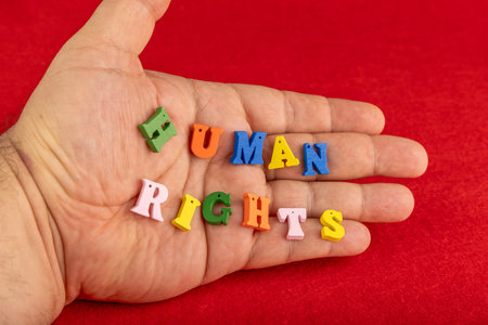 A close-up of a hand holding vibrant wooden letters forming the phrase 'human rights' with a vivid...