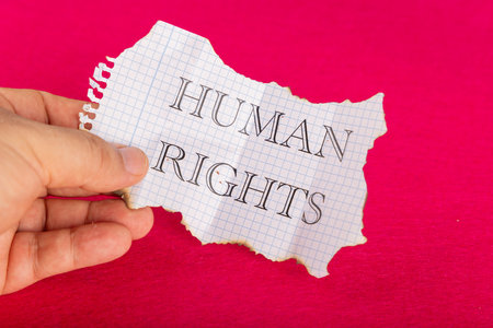 A striking image of a hand grasping a paper with Human Rights printed on it. The paper is burned...