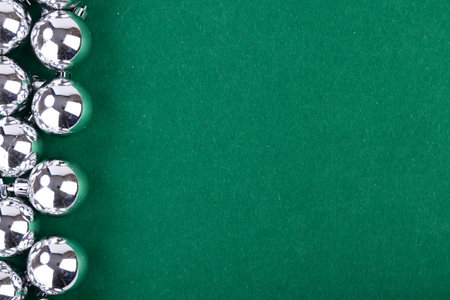 Silver Christmas balls shine brightly against a rich green backdrop, perfect for capturing the...