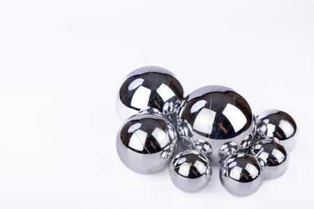 Silver Christmas balls of varying sizes shine against a white background, providing a sleek, festive look perfect for minimalist holiday decorationsの写真素材