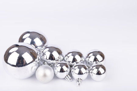 Shiny silver Christmas ornaments of different sizes on a white background, offering a clean and elegant holiday decoration optionの写真素材