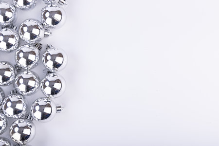 Top view of stunning silver baubles clustered on the left, showing their shine against a bright white surface, ideal for Christmas visualsの写真素材