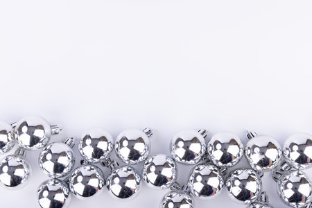 A stunning aerial view of shiny silver Christmas ornaments positioned at the bottom of the frame, set against a crisp white backgroundの写真素材