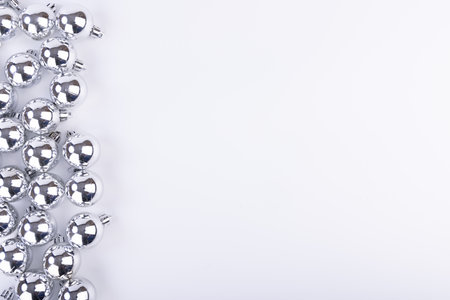 Shimmering silver Christmas balls arranged on the left side, creating a festive atmosphere against a pristine white backgroundの写真素材