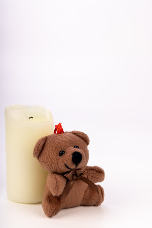 A charming Christmas teddy bear decoration wearing a Santa hat and red scarf, set against a clean white backgroundの写真素材