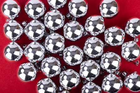A stunning arrangement of silver Christmas balls captured from above, set against a vibrant red backdrop, perfect for festive designsの写真素材