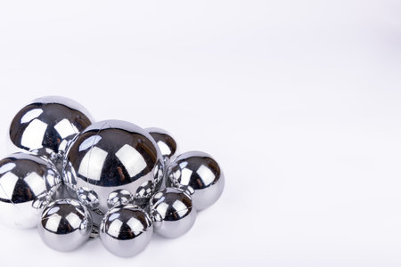 Silver ornaments of different sizes, arranged on a white background, reflecting light in a minimalist and elegant styleの写真素材