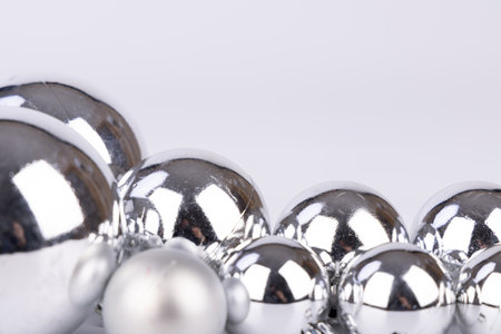 Silver Christmas ornaments in multiple sizes placed on a white backdrop, giving a simple yet sophisticated holiday vibeの写真素材