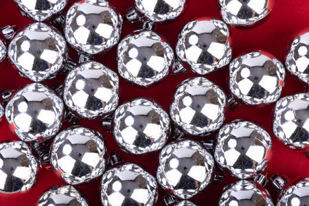 A captivating top-down view of shimmering silver Christmas balls, enhancing the holiday spirit against a bold red backgroundの写真素材