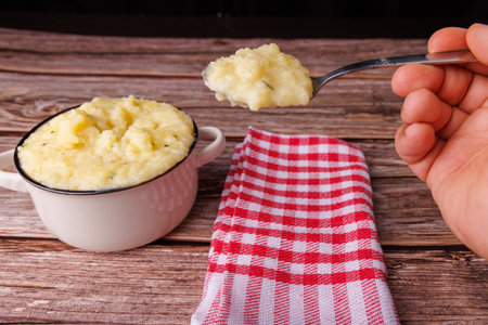 A hand takes a spoonful of mashed potatoes from a rustic bowl, emphasizing comfort and togetherness...