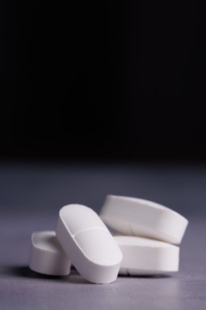 Close-up image of white tablets on a concrete table, displaying their details and smooth surfaces,...