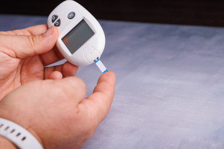 A close-up image of an individual checking blood glucose on a concrete surface, capturing the...