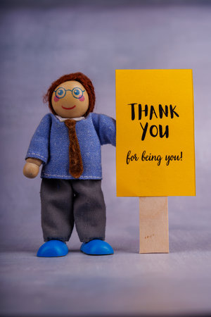 A wooden toy man holds a yellow sign with motivational words, spreading positivity and hope, in a simple, minimalist settingの写真素材