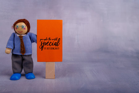 The cheerful wooden toy man showcases a red banner, featuring a positive message that motivates and encourages viewers to pursue their dreamsの写真素材
