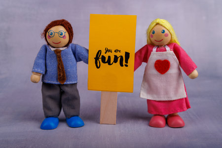 A wooden toy couple displays a yellow banner with a positive message, radiating happiness and motivation, creating an inspiring and cheerful atmosphereの写真素材