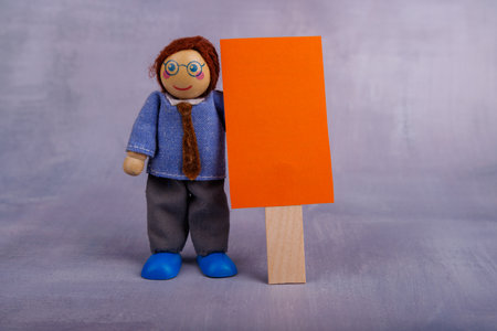 A cheerful wooden toy figure holds a white banner with red lettering, showing a message of positivity against a bright background, conveying joyの写真素材