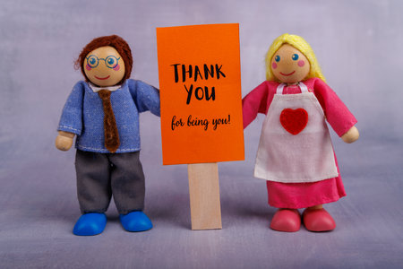 A wooden toy man and woman hold a red motivational banner, conveying a positive message, radiating joy and inspiration in the sceneの写真素材