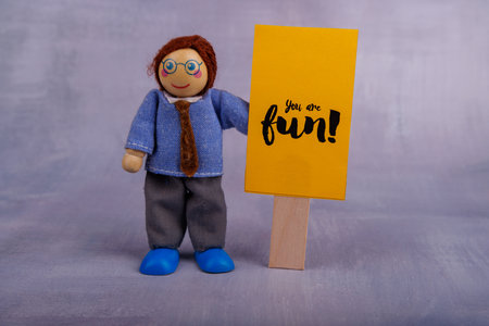 A charming wooden toy figure showcases a bright yellow banner with an inspiring quote, highlighting positivity and encouragement in a cheerful wayの写真素材