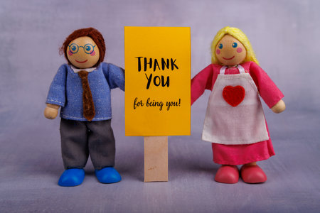 A charming wooden couple holds a bright yellow banner displaying an uplifting quote, symbolizing encouragement and positivity in a delightful wayの写真素材