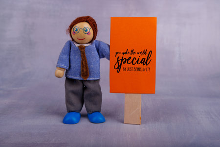 The wooden toy figure proudly displays a red motivational banner, spreading positivity and joy, making it an ideal symbol of encouragementの写真素材
