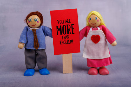 The wooden toy figures, a man and woman, proudly display a red motivational sign, encouraging positivity and warmth in the sceneの写真素材