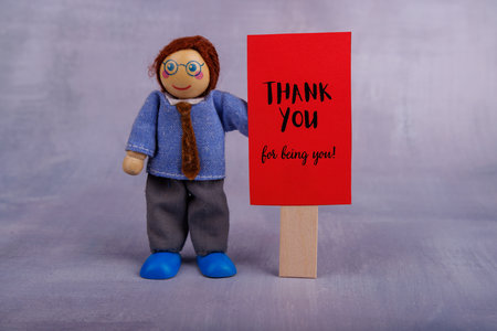 This wooden toy man holds a vibrant red banner with a motivational message, conveying positivity and inspiration for everyone who sees itの写真素材