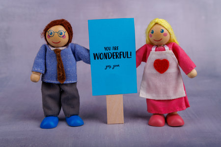 The wooden toy couple displays a blue banner with an inspirational quote, conveying joy and support...