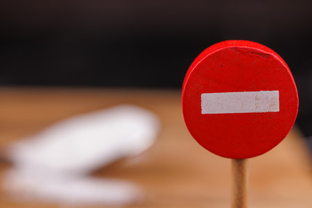 A close-up of a wooden no-entry sign with a spoonful of sugar on a wooden surface, symbolizing...
